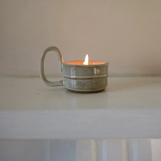 Hand crafted artisanal hand glazed ceramic tea light holder designed for a small pillar or tea light candle but pictured with a lit tea light inside it.