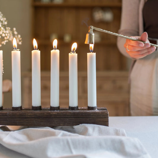 Candles being put out with an exquisite brass hand forged candle snuffer.