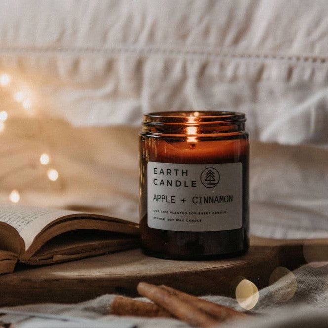 Ethically sourced soy wax candle in glass jar burning with a soft flame and labelled as apple & cinnamon scent.