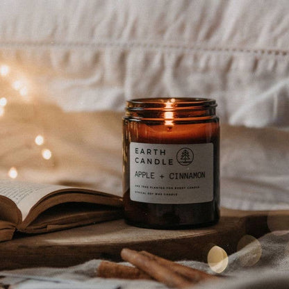 Ethically sourced soy wax candle in glass jar burning with a soft flame and labelled as apple & cinnamon scent.