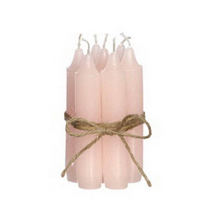 Set of pink candles tied with twine on a white background