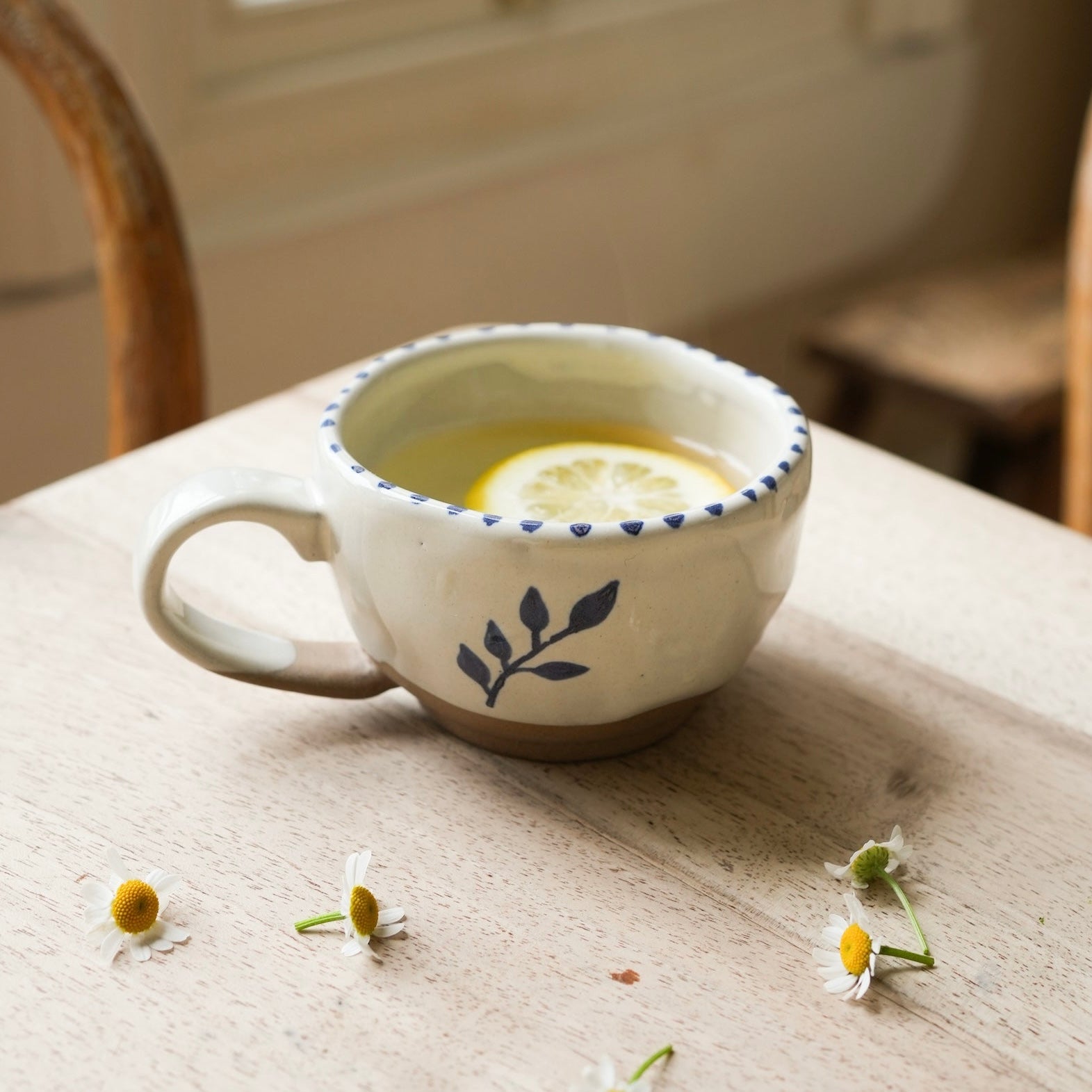 Hand painted natural glazed ceramic stoneware tea cup, with a simple botanical motif hand painted in Indian ink. Brush stroke stripe effect around the cup rim and the cup is pictured with an antique brass spoon.