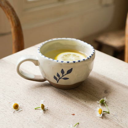 Hand painted natural glazed ceramic stoneware tea cup, with a simple botanical motif hand painted in Indian ink. Brush stroke stripe effect around the cup rim and the cup is pictured with an antique brass spoon.