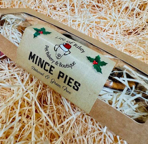 Packaged mince pies for dogs with a label on a bed of straw