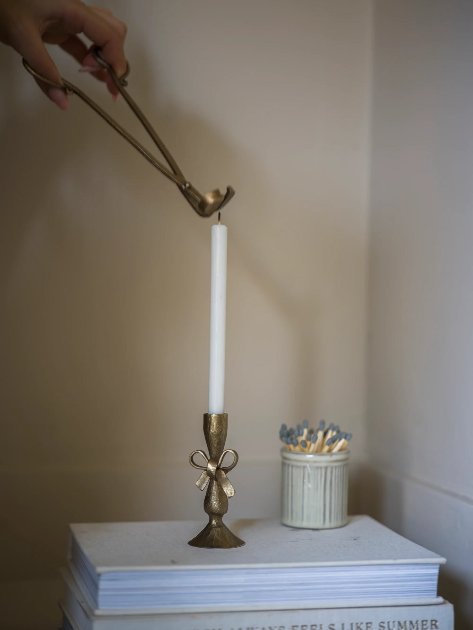Bronze candle holder with a white candle on a stack of books against a plain background