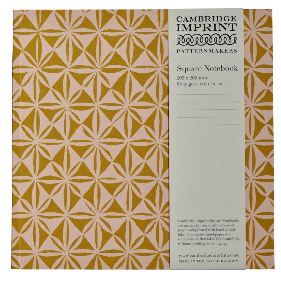 Cambridge Imprint patterned notebook with geometric design in pink and mustard with a paper belly band label describing the product. 