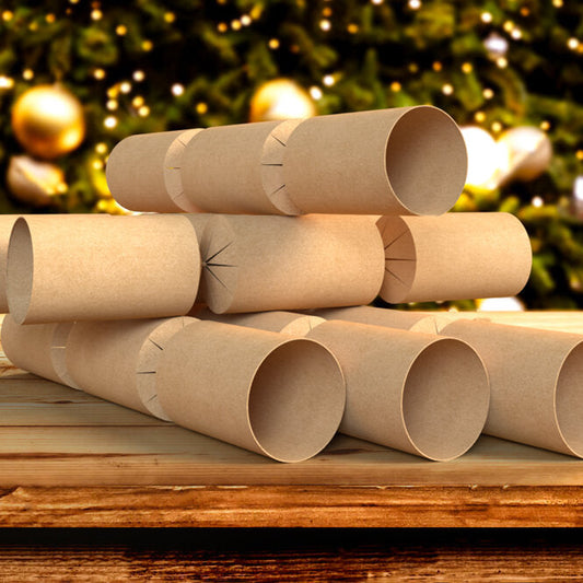Stack of brown kraft boards with pre-cut holes for inserting into Christmas crackers, placed on a wooden surface with a festive background.